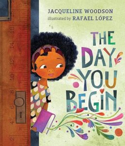 Cover of ‘The Day You Begin’ with an illustration of diverse children sharing stories in a classroom setting.